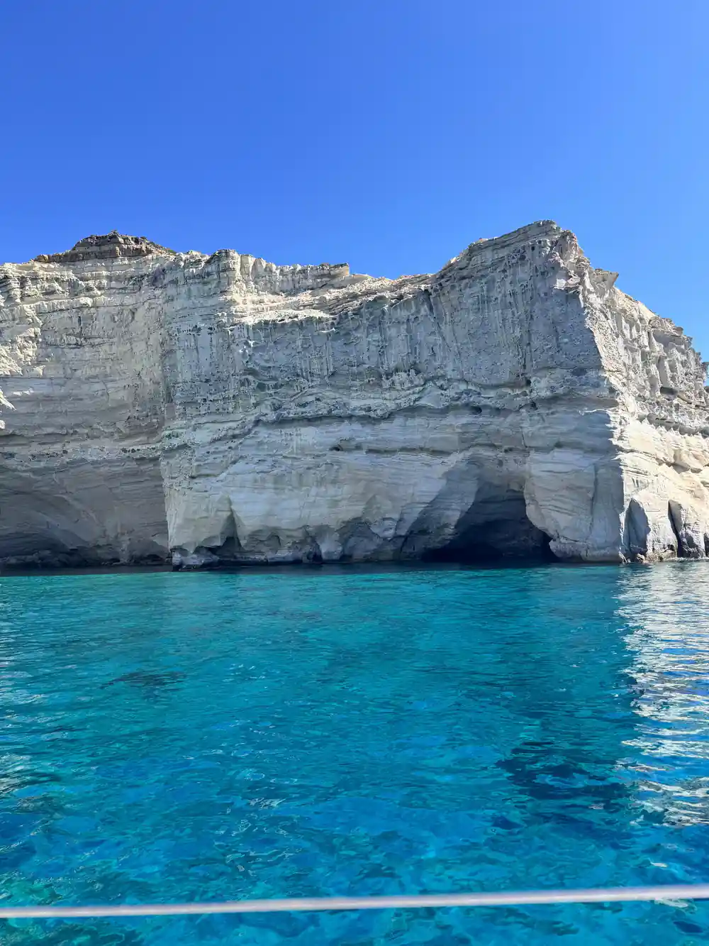 Banded white cliff dropping into turquoise water