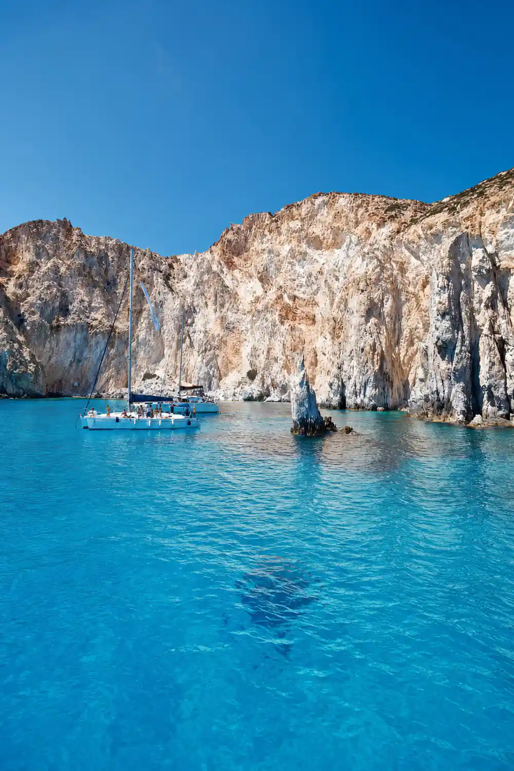 Boats anchored below a streaked white and pink cliff