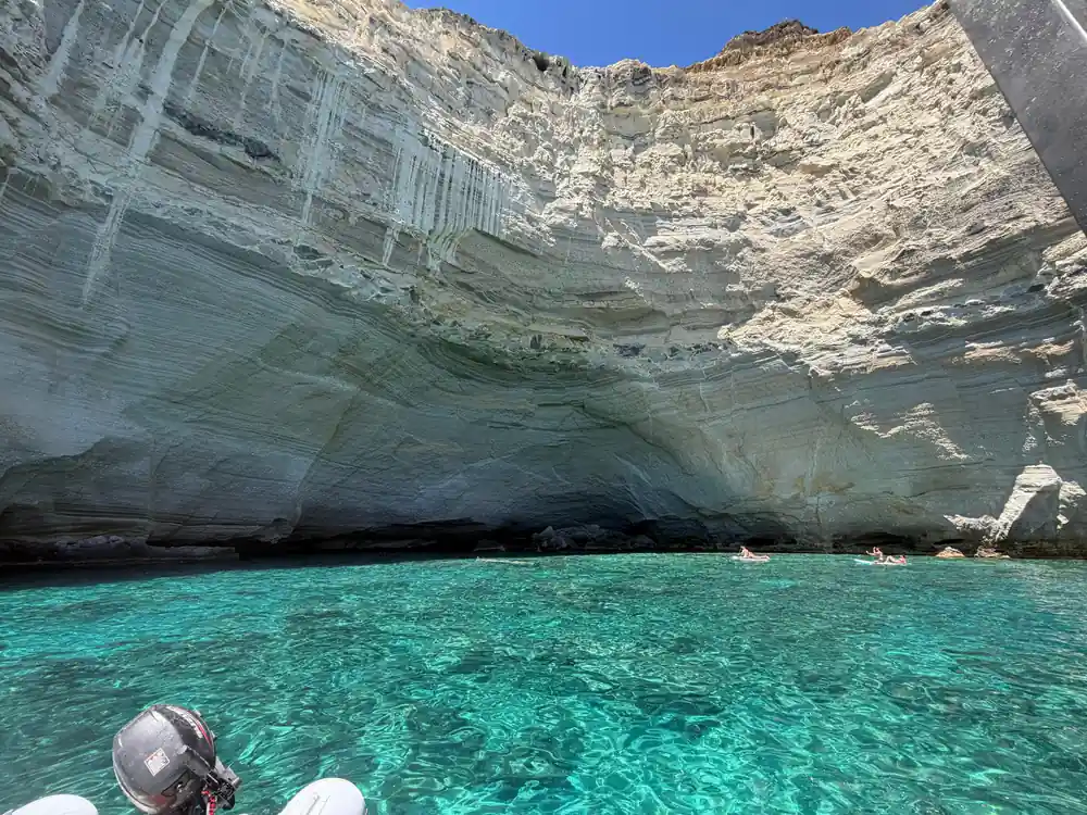 Curved white cliff wall enclosing bright green water