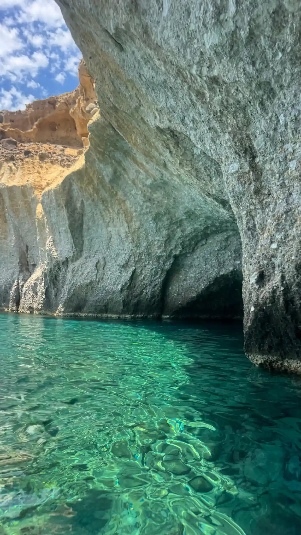 Green water inside a cave under ochre-stained rock