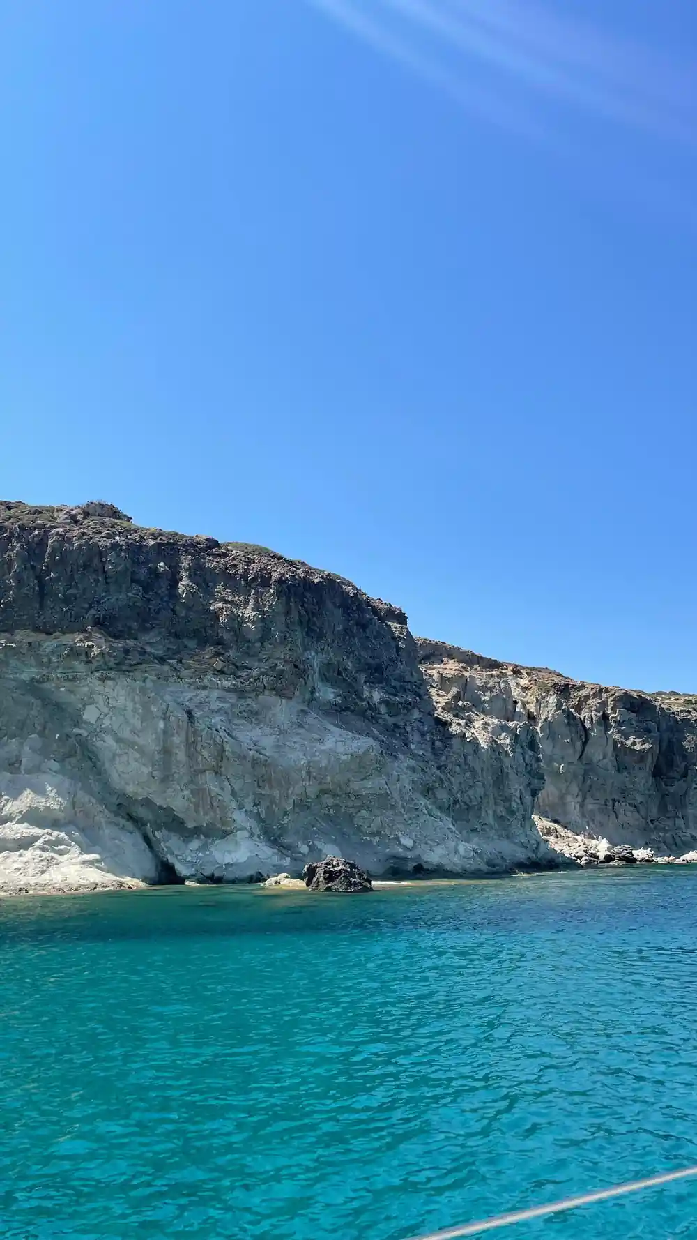 Long white cliff running down to a turquoise shore