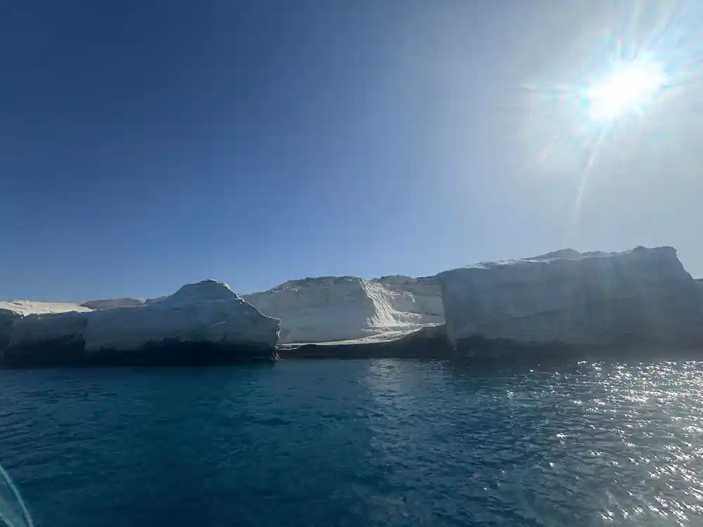 Low white cliffs along a dark sea under bright sun