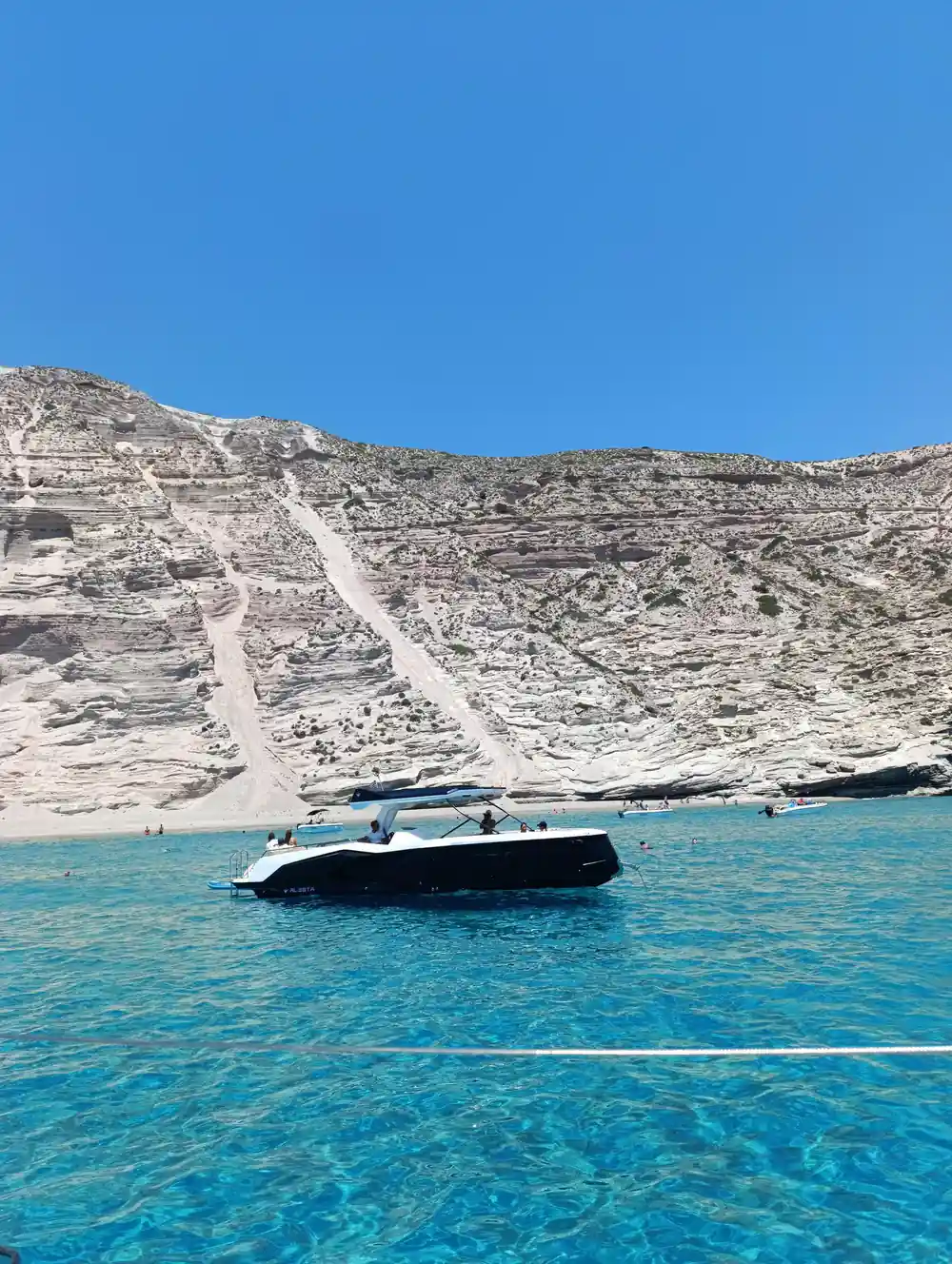 Motor boat below a smooth white rock slope