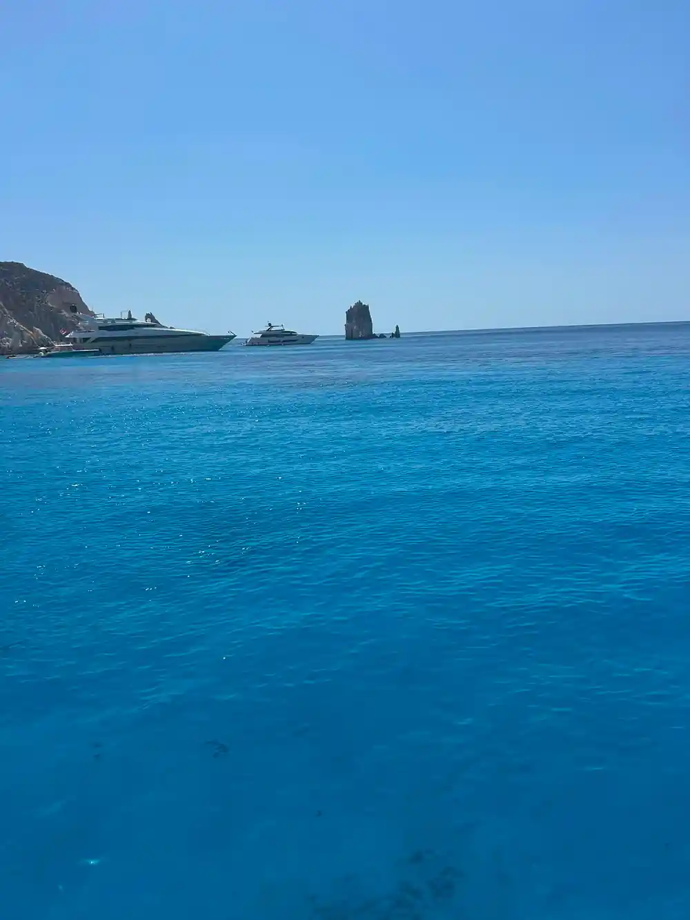 Motor yachts and a distant rock pinnacle on open water