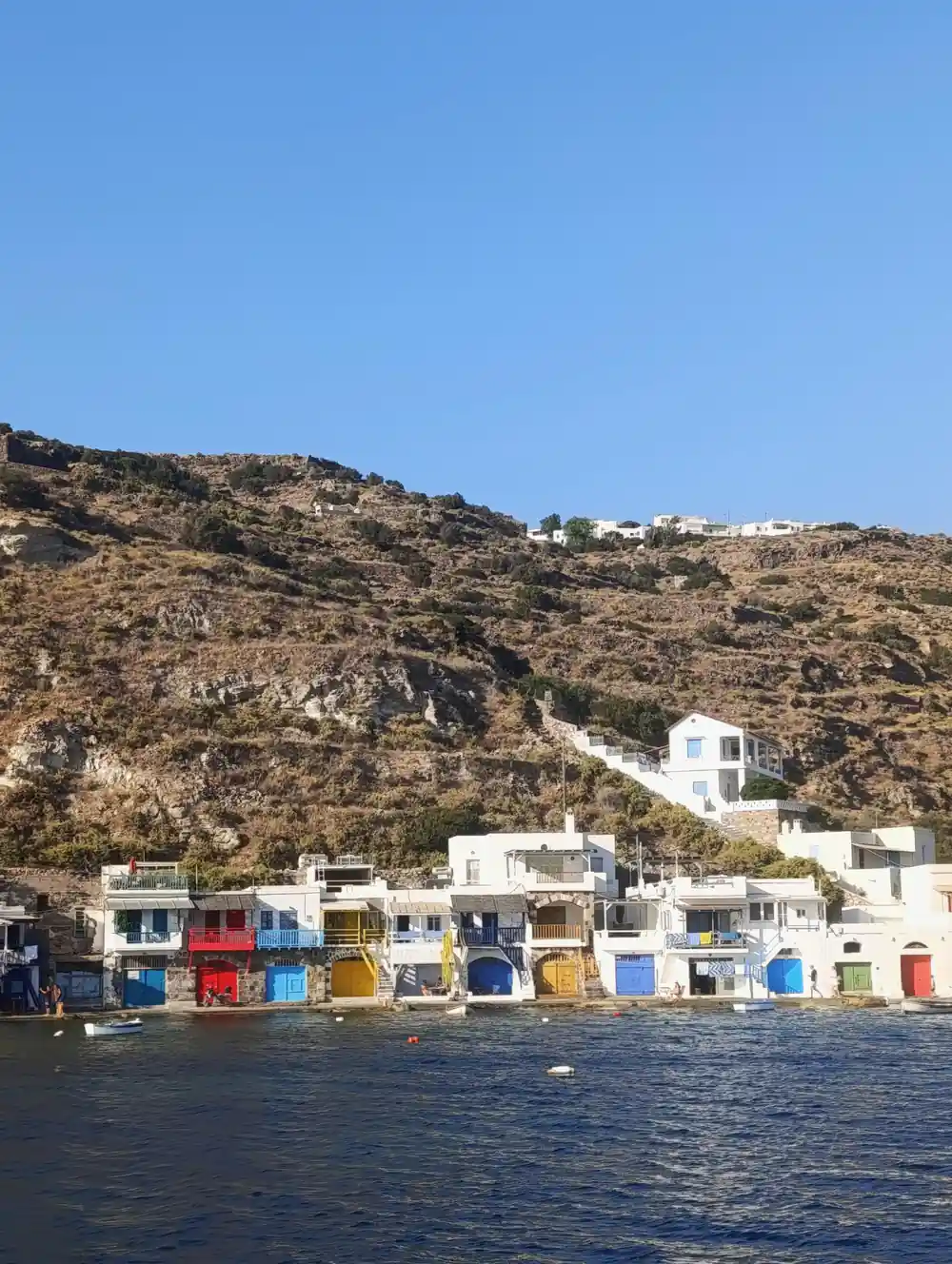Painted boathouses below a village on the hillside