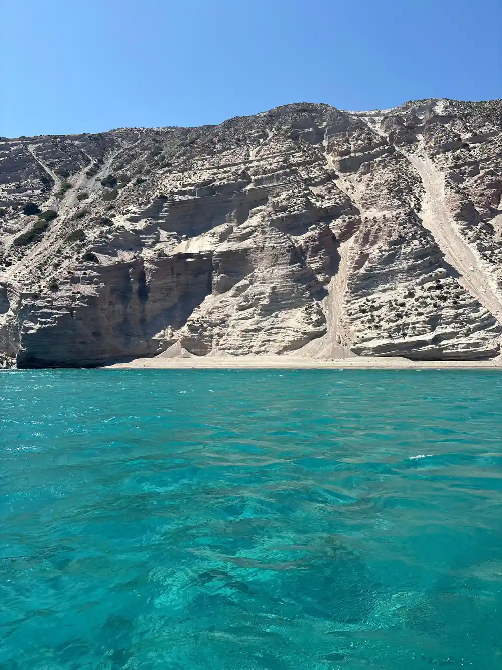 Pale cliff and scree slope above a turquoise shore