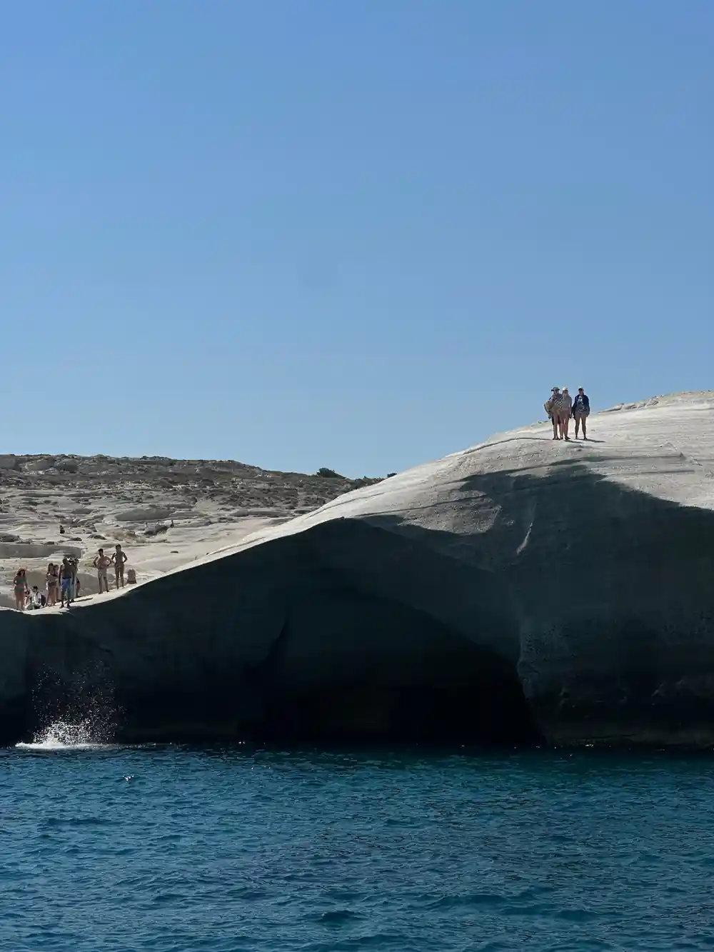 People on a smooth white rock dome above the sea