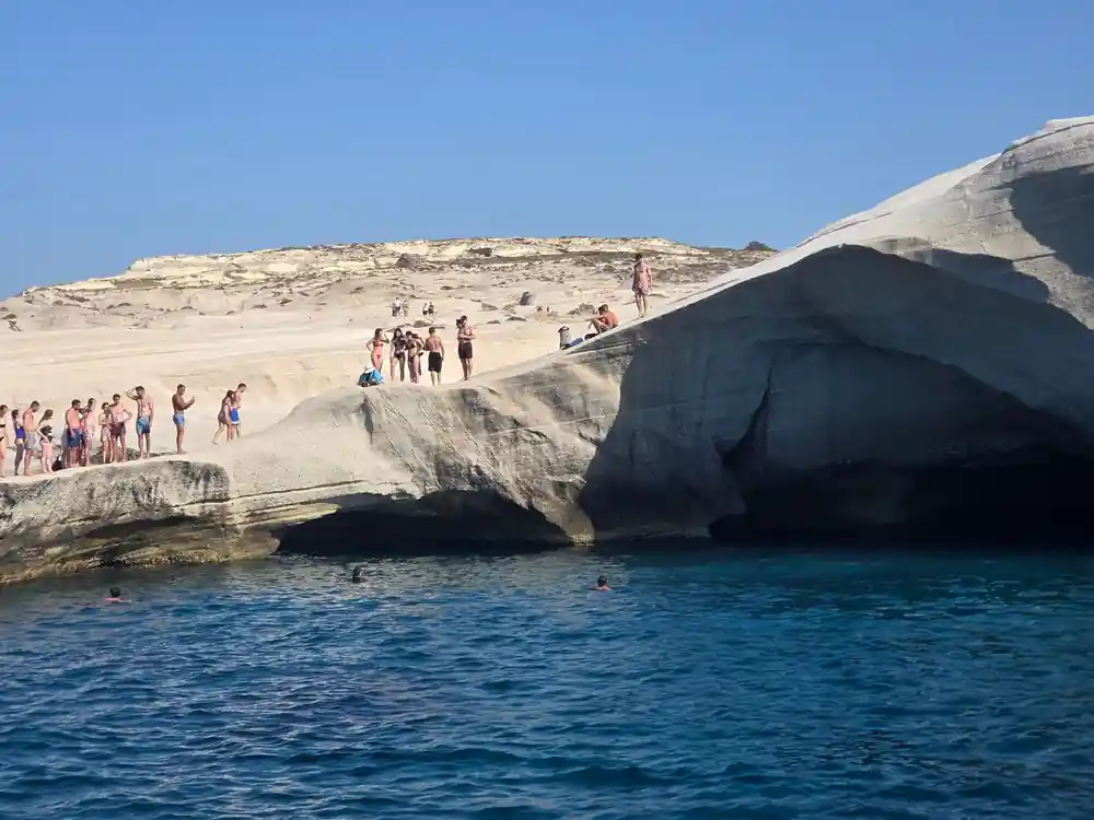 People on the white rock above a swimming bay