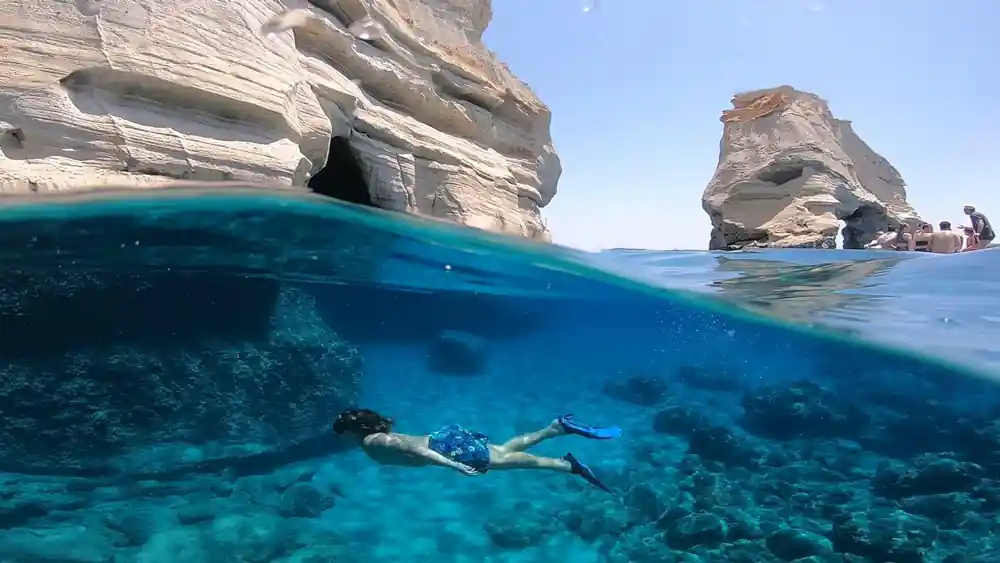Split shot of a snorkeller below white rock stacks