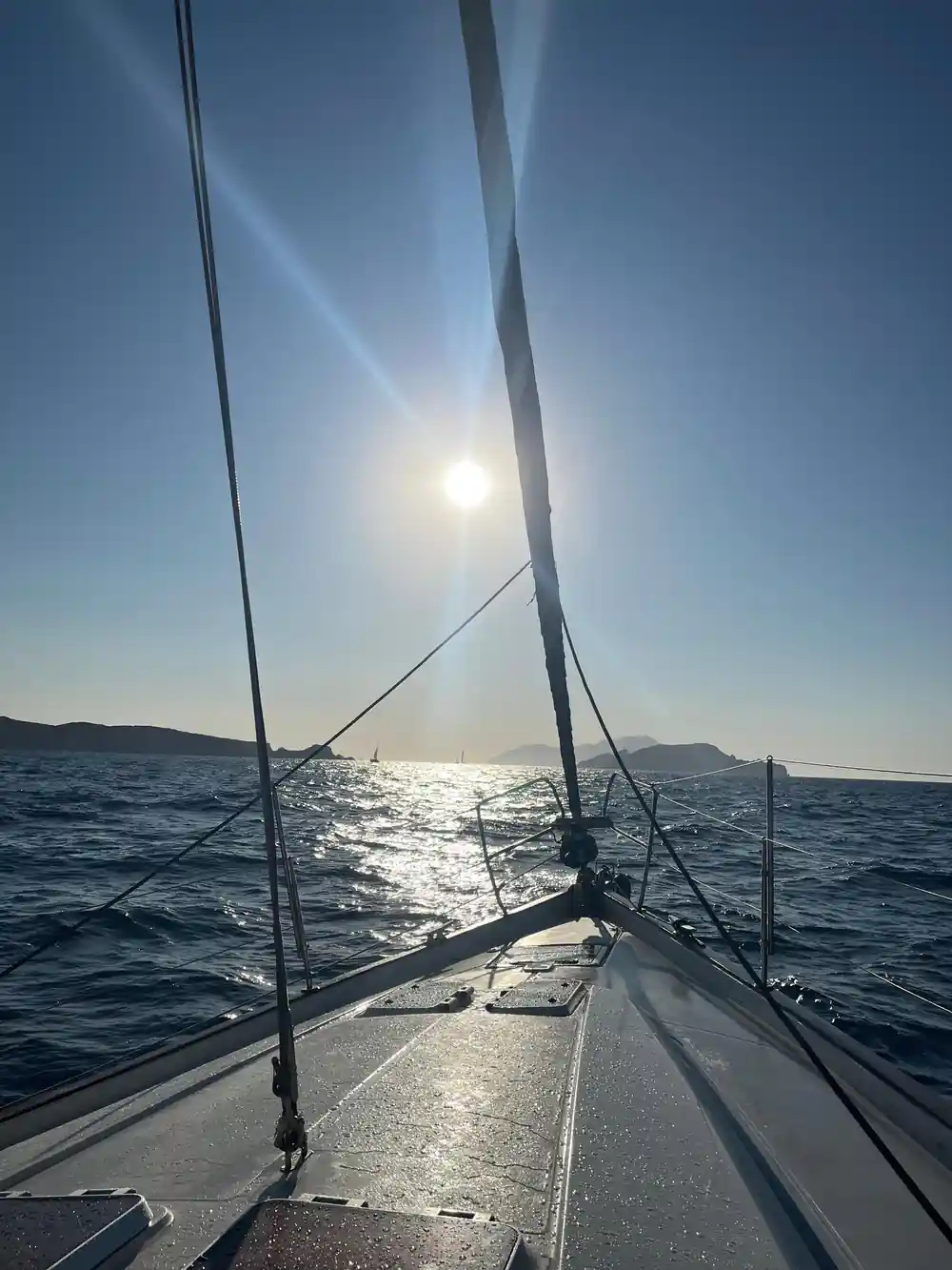 Sun low over the sea past the mast and foredeck