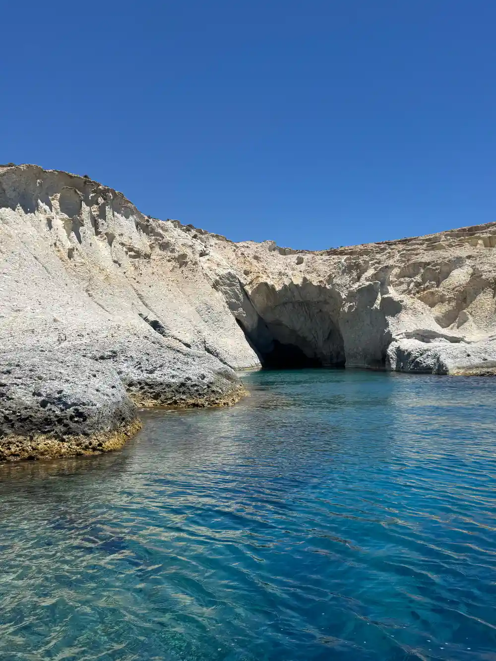 White cliff with a dark cave mouth at water level