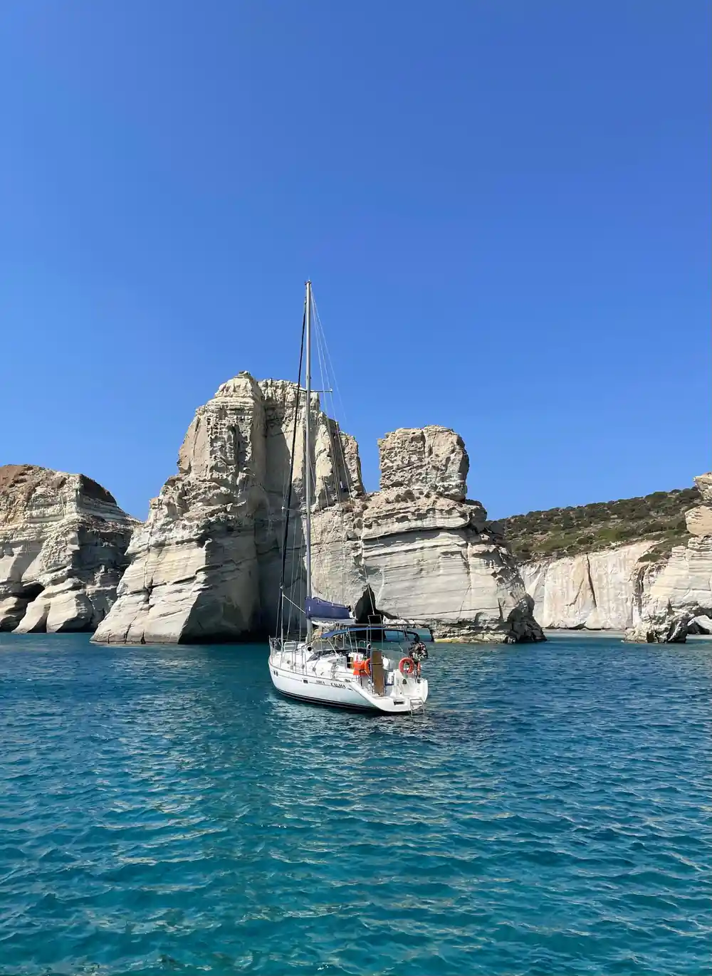 White rock stacks and arches above a yacht at anchor