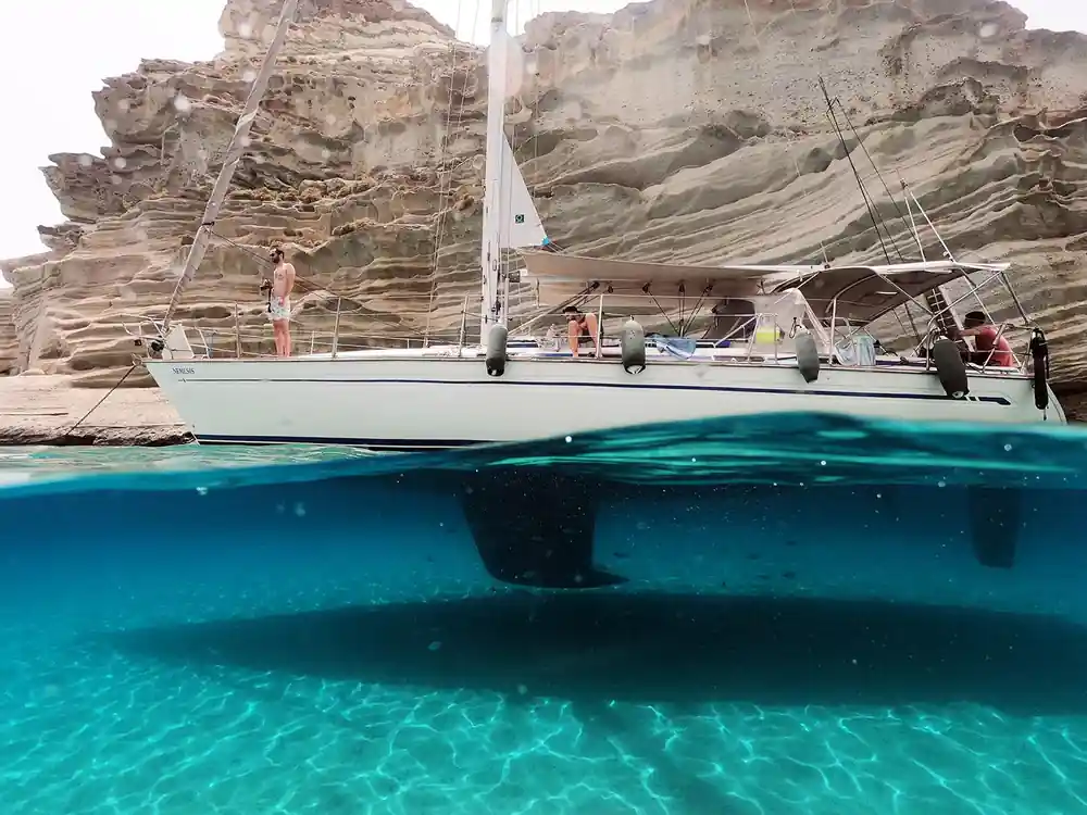 Yacht at anchor over pale sand in bright turquoise water