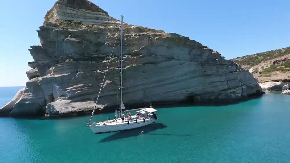 Yacht anchored close under a striped white cliff