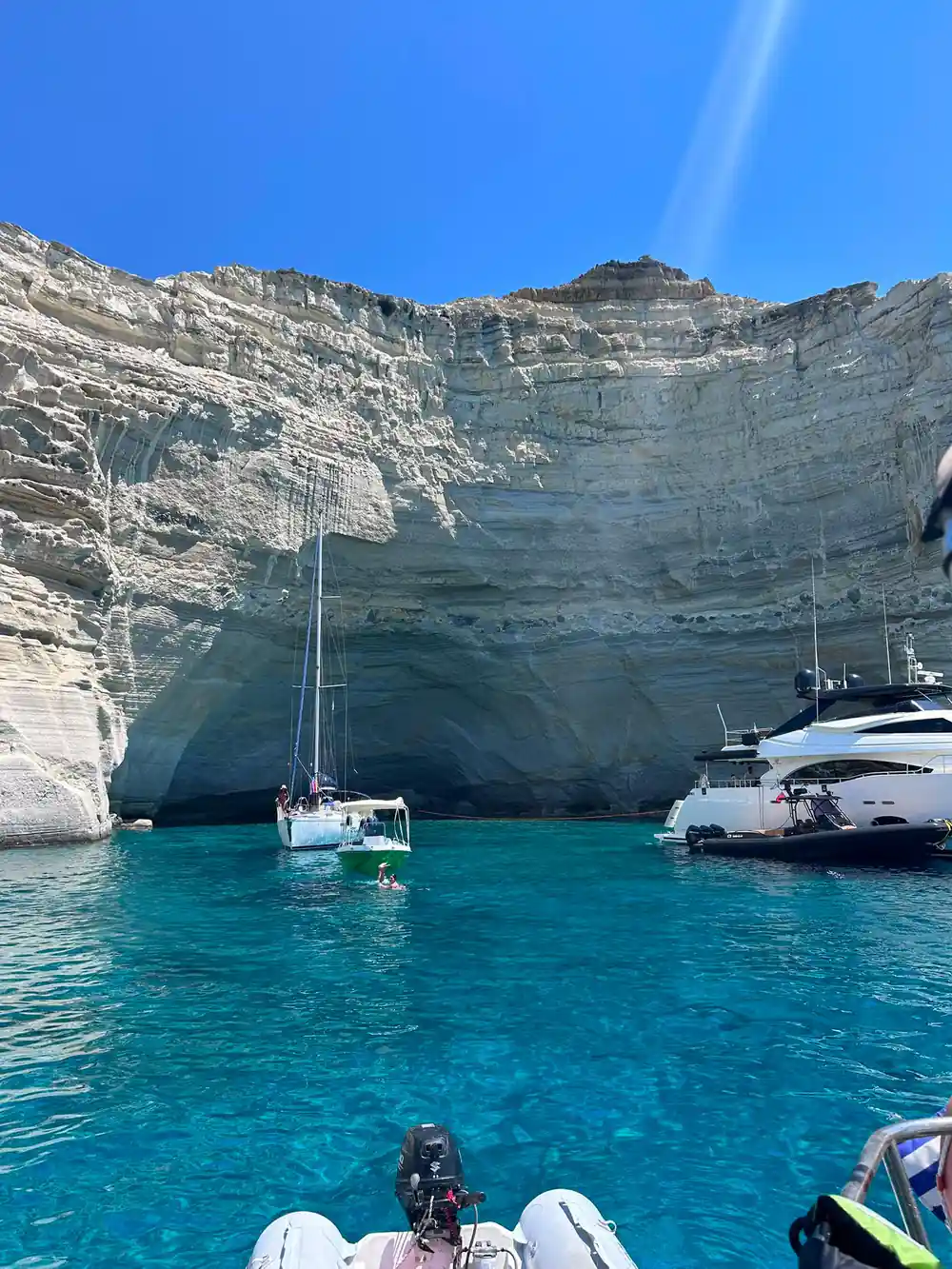 Yacht and motor boat below a towering white cliff