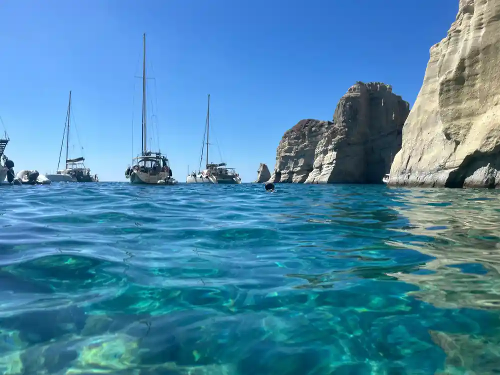 Yachts anchored among white rock stacks in clear water