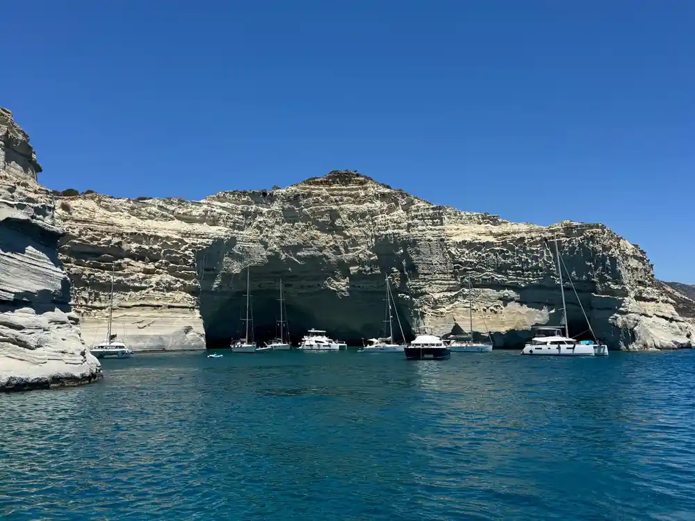 Yachts anchored beneath a banded white cliff