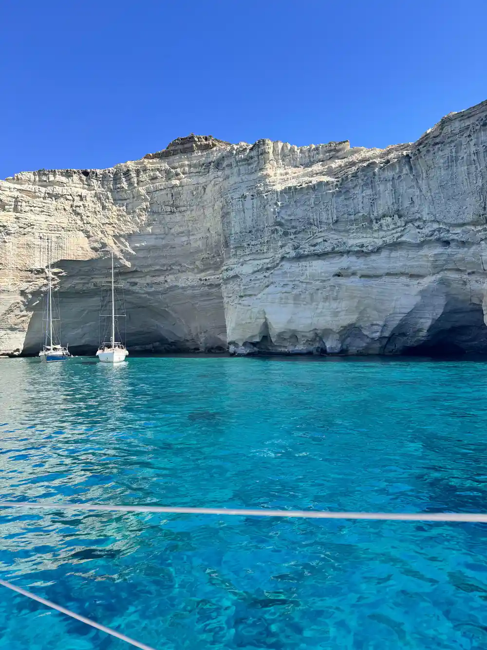 Yachts moored below a long white cliff wall